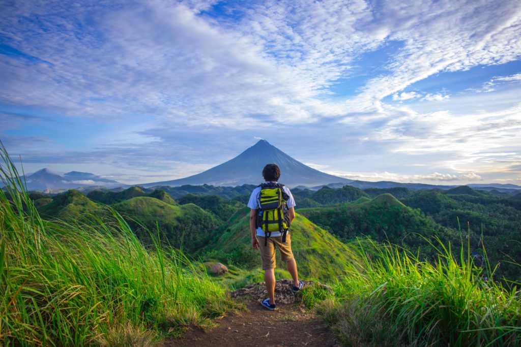 young man hiking with volcano in the distance